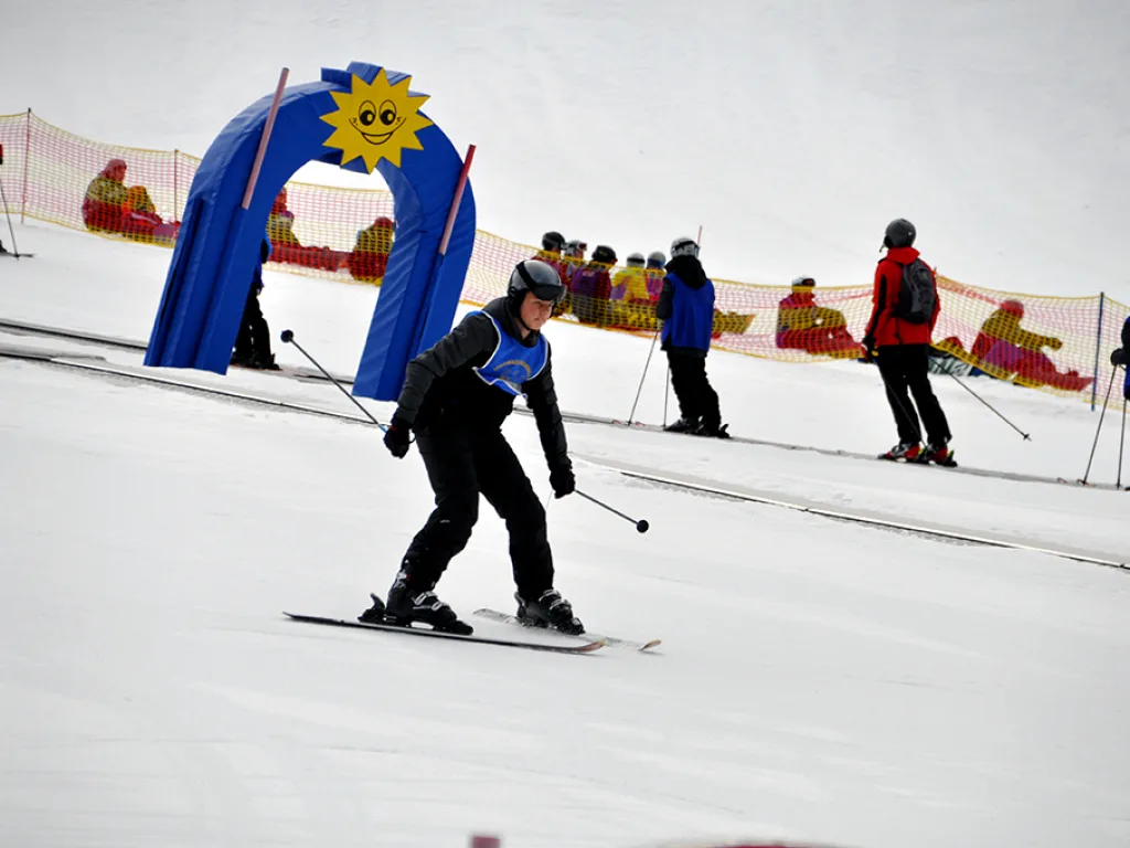 Skifahrer fährt an einer blauen Kulisse mit Sonnenmotiv vorbei.